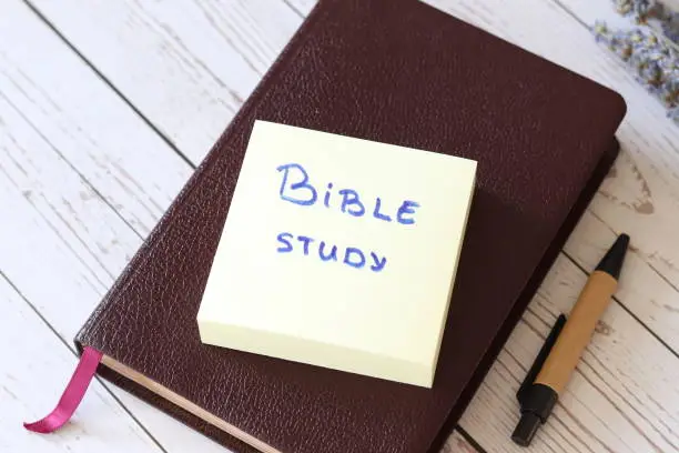 Bible study daily. Studying and learning the Word of God and Jesus Christ. Life lessons, wisdom, knowledge. Inspiring handwritten note message with pen on wooden background. Biblical concept.