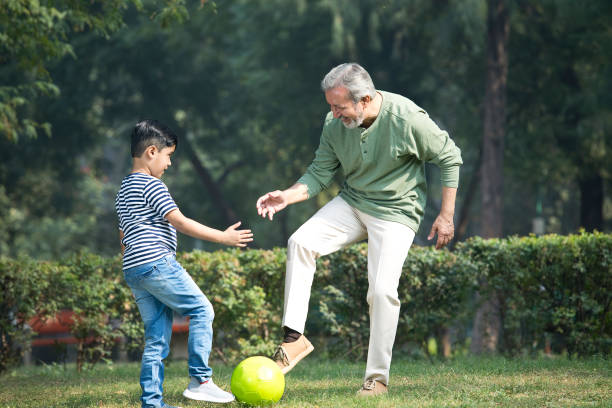 homme âgé jouant avec son petit-fils au parc - leisure activity grandparent grandfather grandson photos et images de collection