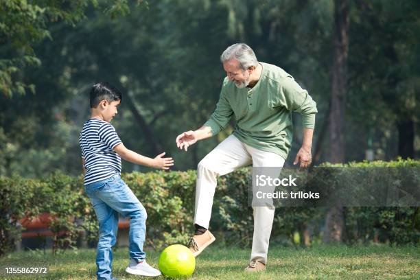 Senior Man Playing With Grandson At Park Stock Photo - Download Image Now - Playful, Playing, Child