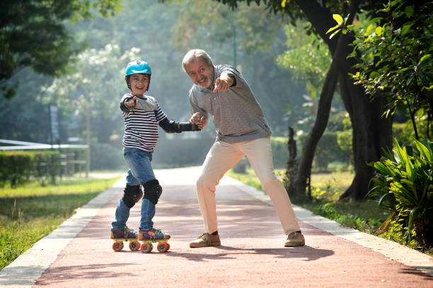 Grandfather holding hand of his grandson and assisting in skating at park