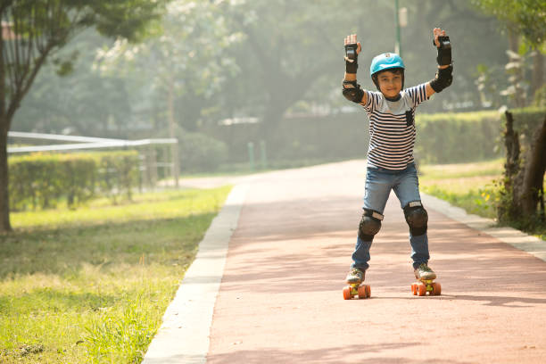 Boy learning roller skating at park stock photo