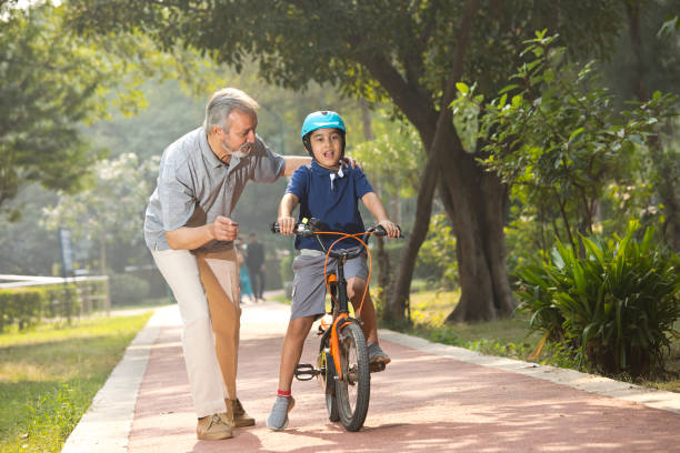 istock Boy learning bicycle with assistance of grandfather at park 1355870990