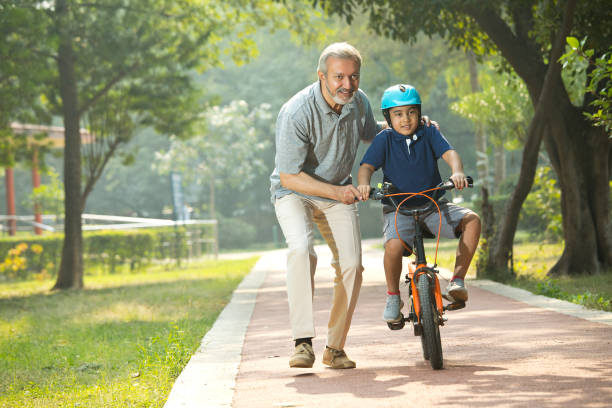 istock Boy learning bicycle with assistance of grandfather at park 1355871004