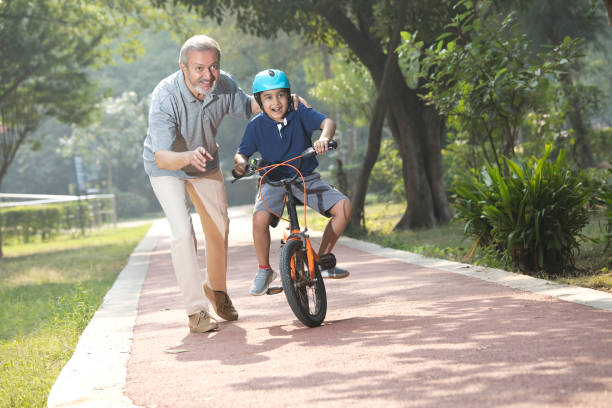 istock Boy learning bicycle with assistance of grandfather at park 1355871025