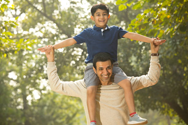 istock Father carrying son on shoulders at park 1355871119