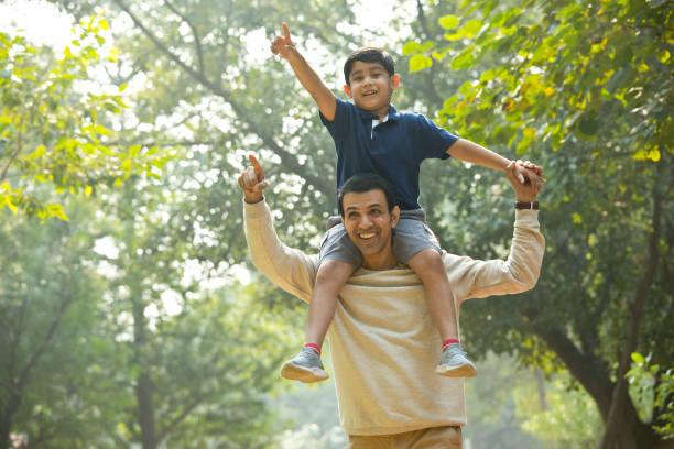 istock Father carrying son on shoulders looking at view at park 1355871143