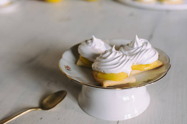 вкусный лимонный пирог отдельными порциями на круглой тарелке на сервированном столе - lemon meringue pie pie pastry crust portion стоковые фото и изображения