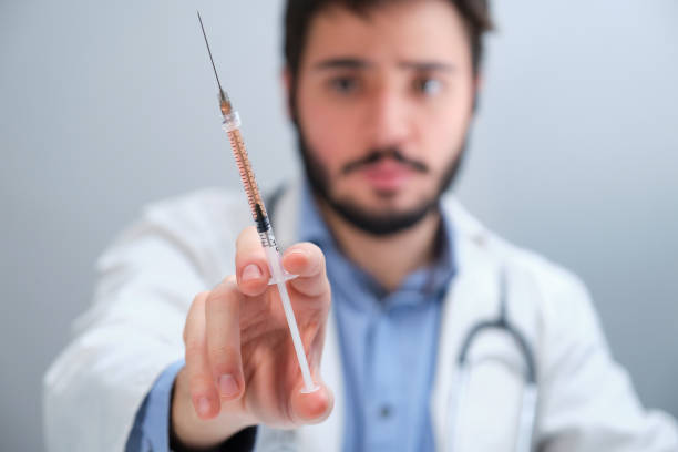 istock Unrecognizable doctor holding a syringe with an orange liquid. 1355874499