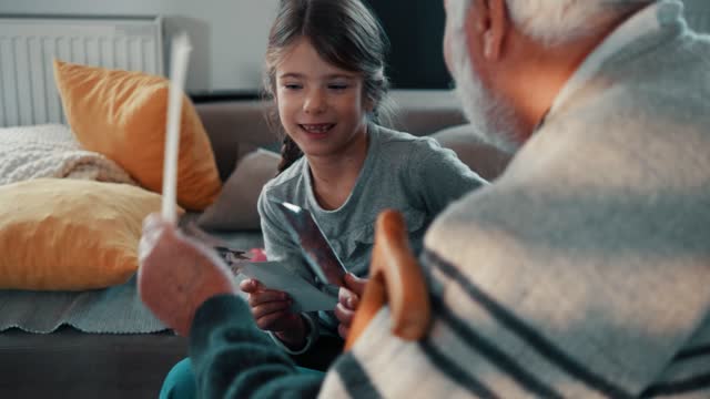 Grandfather shows his child granddaughter who her ancestors are by looking at old pictures from the past