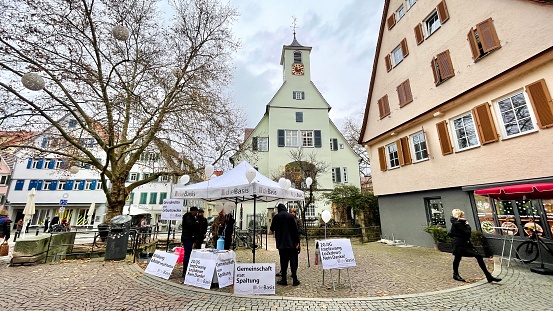 Tübingen, Germany - November, 27 - 2021:   Houses and street in the old town. An information stand of a new movement, Die Basis, to be seen.
