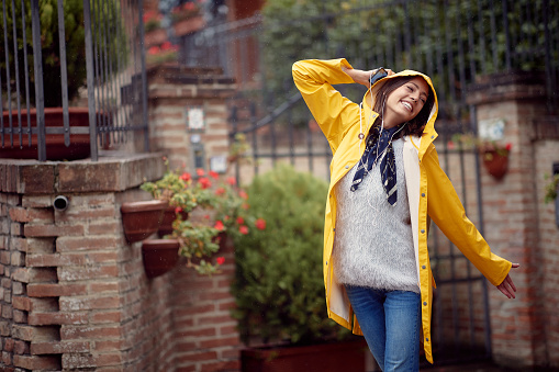 A young girl in a street walk on a cloudy day is in a good mood while enjoying music and rain. Walk, rain, city