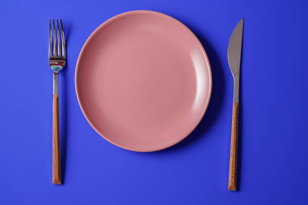 istock Empty plate and a cutlery set on blue paper background. 1355876720