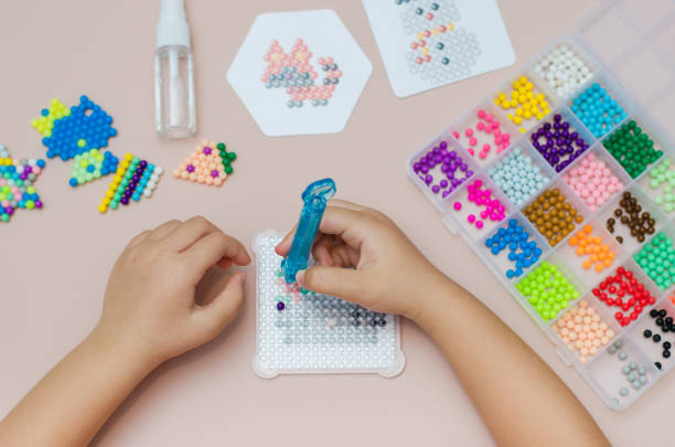 istock Children's educational game aqua mosaic, a small child inserts multicolored beads into the pattern with a special pen. 1355878745