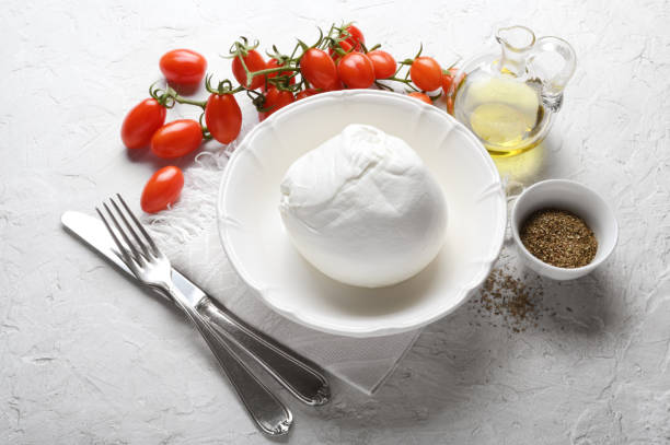 istock Buffalo mozzarella, cherry tomatoes, extra virgin olive oil and oregano on white plaster background. 1355889086