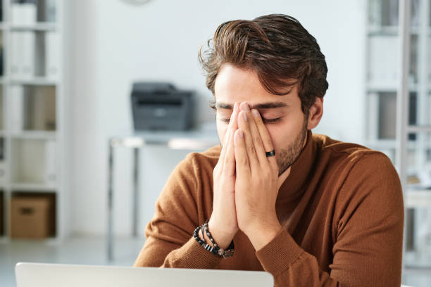 istock Confused young middle eastern manager with stubble being stressed out and covering face with hands in office 1355897596
