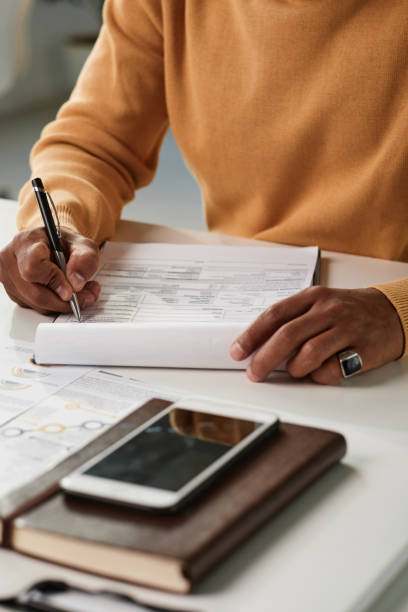 istock Close-up of unrecognizable black man in ring sitting at table and filling application form 1355897703