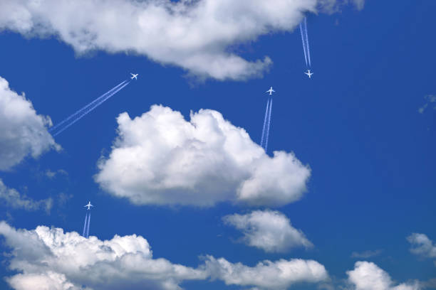 Many distant passenger jet planes flying on high altitude on clear blue sky leaving white smoke trace of contrail behind. Busy air transportation concept.