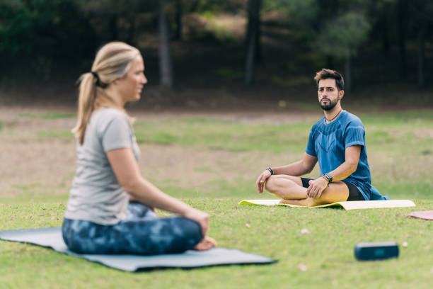 istock Man doing yoga with a female instructor in a forest 1355903023