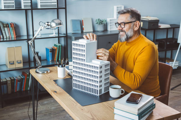 Business man building a project Mature man at office making building model for next project. architectural model house stock pictures, royalty-free photos & images