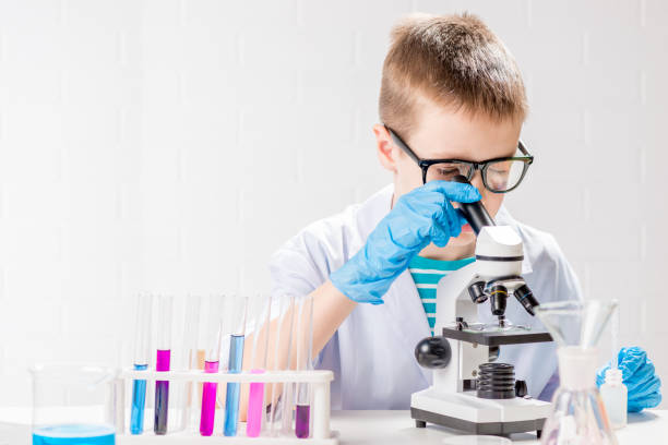 istock A schoolboy with a microscope examines chemicals in test tubes, conducts experiments - a portrait on a white background. Concept for the study of coronavirus in the laboratory 1355909919