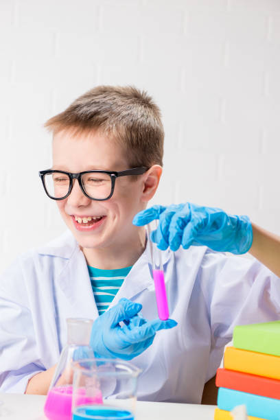 istock A schoolboy studies multi-colored substances in test tubes, conducts experiments - a portrait on a white background. Concept for the study of coronavirus in the laboratory 1355909926