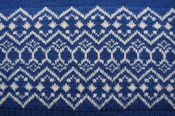 istock Jacquard knitted pattern. Knitted with white thread rhombuses and zigzags on a blue background. Geometric ornament for Christmas or New Year. Winter trendy modern traditional folk clothing ornament 1355910182