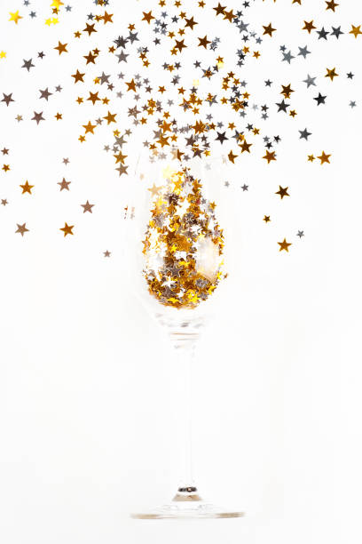 istock Christmas background.Simple minimalistic Christmas home decor.Flat lay,top view.Festive composition of a glass of champagne and glitter on a light background.Copy space. 1355910451