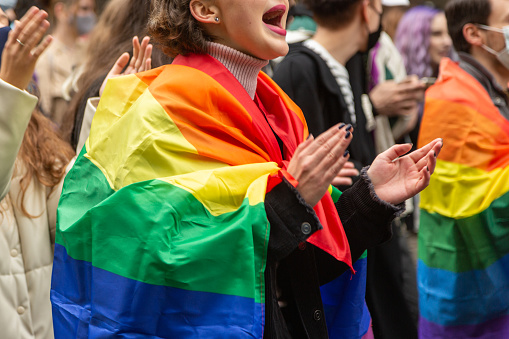 Kyiv, Ukraine - 09.19.2021: A girl supporting the LGBTQ rally in Kyiv, wrapped in a rainbow flag during the Pride Parade. Concept LGBTQ.