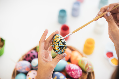 Asian young pretty woman enjoy painting a water colors on fantasy eggs for Easter egg festival. Beautiful colorful fancy Easter egg in bucket. The symbolic of Easter egg festival concept.