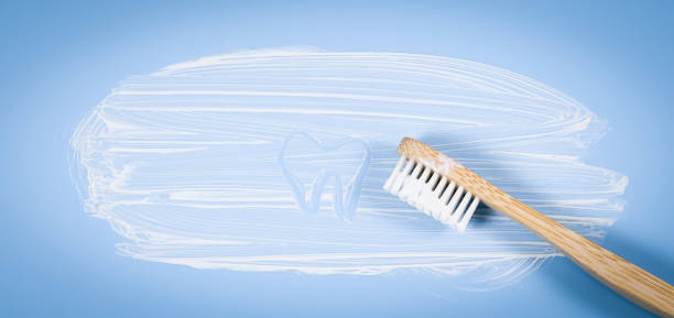 istock Bamboo toothbrush with smeared toothpaste and a painted tooth on a soft blue background 1355923629