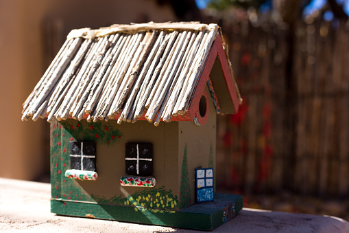 Miniature house. Souvenir, rustic plastic home on gray background. Toy colorful farmhouse. Close-up. Selective focus. Copy space.