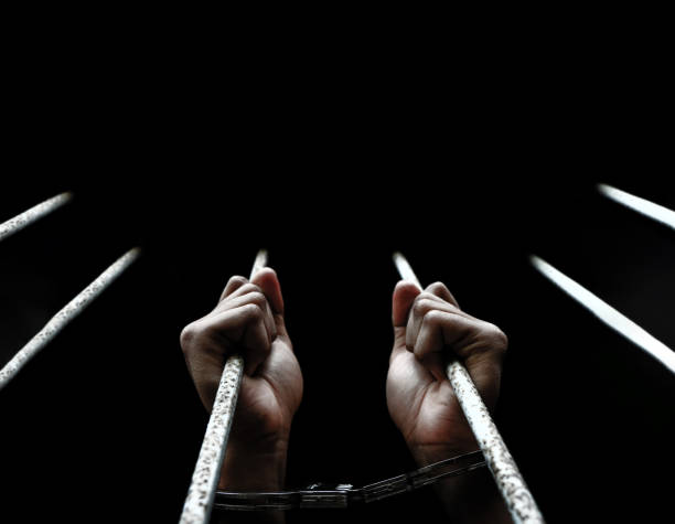 istock prisoner hands holding metal bar at the prison 1355935759