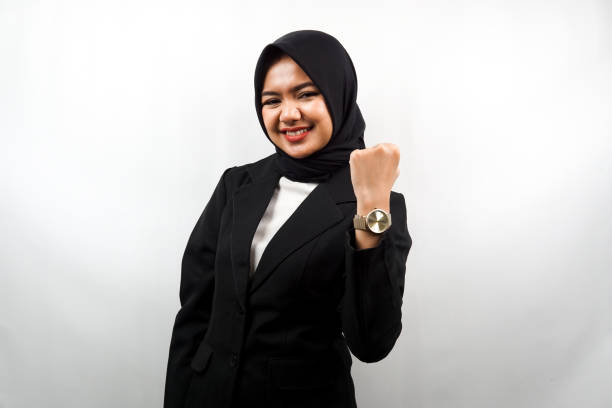 beautiful young asian muslim business woman smiling confident, enthusiastic and cheerful with hands clenched, sign of success, punching, fighting, not afraid, victory, isolated on white background - japanese ethnicity women asian and indian ethnicities smiling imagens e fotografias de stock