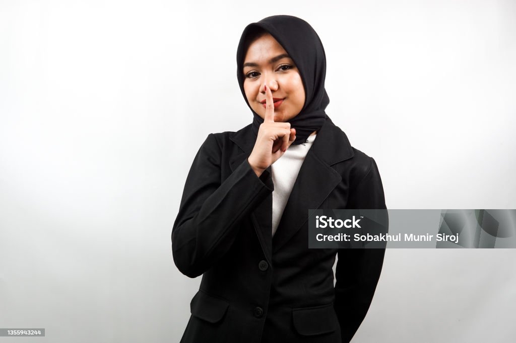 Beautiful asian young muslim business woman with finger on mouth, telling to be quiet, don't make noise, lower your voice, don't talk, isolated on white background 20-24 Years Stock Photo
