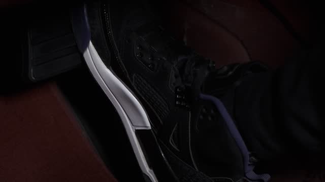 A guy in sneakers presses the gas and brake pedals close-up