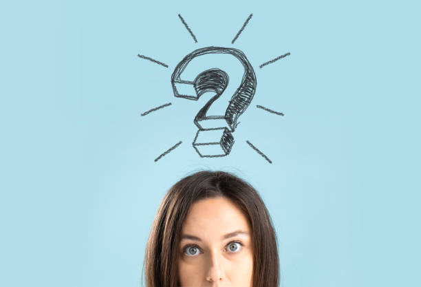 Close up of a confused young woman standing on blue background with a large question mark above her head