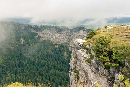 view from the famous Creux du Van canyon and his rock walls that drop vertically around 160 meters, in the swiss jura mountains near Lake Neuchâtel, between the cantons of Neuchatel and Vaud, Switzerland.