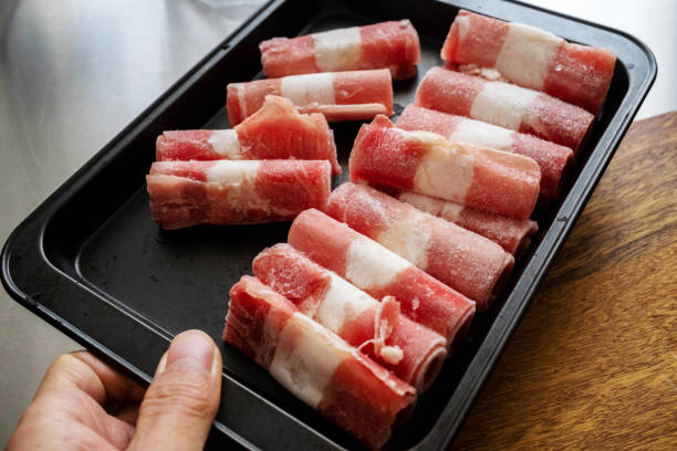 Frozen Mutton Rolls hand holding prepared frozen mutton rolls in cooking pan, ready for cooking mutton roll for chinese hot pot stock pictures, royalty-free photos & images
