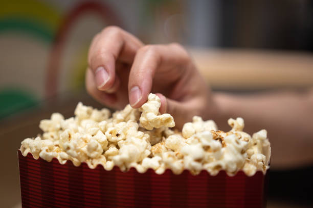 istock Picking up a piece of popcorn from the box. 1355958083
