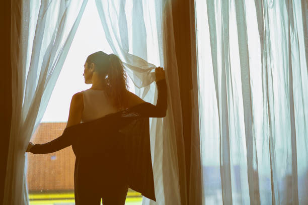 istock Young woman looking out the window 1355958717