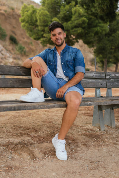 istock Young man sitting on a bench of a viewpoint looking at the camera. 1355958950
