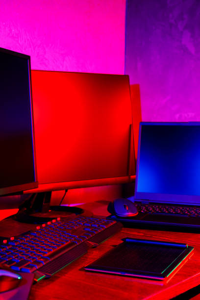 istock Graphic designer workplace in neon light. Computer equipment and graphics tablet for content creation. Freelancer home office in pink blue light. Home office concept 1355959728