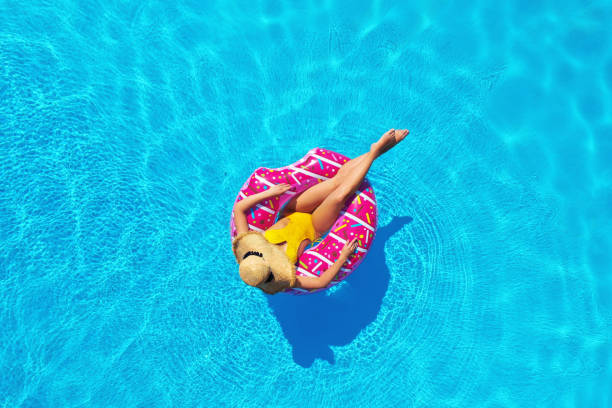 mujer joven con anillo inflable en la piscina, vista superior - pink hat fotografías e imágenes de stock
