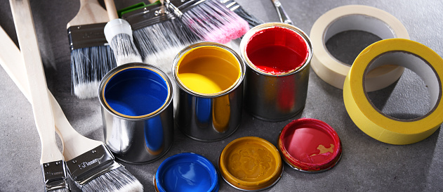 Paint cans and paintbrushes of different size  for home decorating purposes.