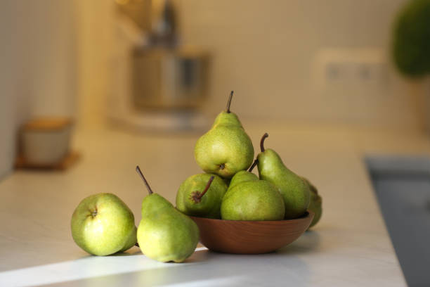 istock Fresh ripe pears on white countertop in kitchen 1355964700