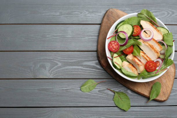 istock Delicious salad with chicken and vegetables on grey wooden table, flat lay. Space for text 1355964707