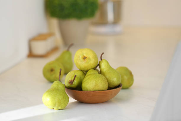 Fresh ripe pears on white countertop in kitchen