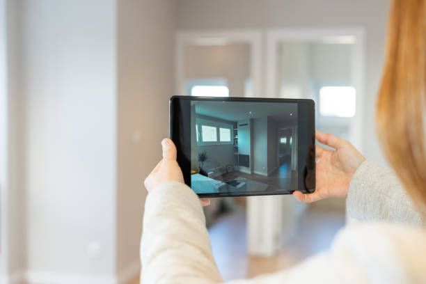 Real estate agent conducts a virtual tour to show a property to clients with a video call using his digital tablet stock photo