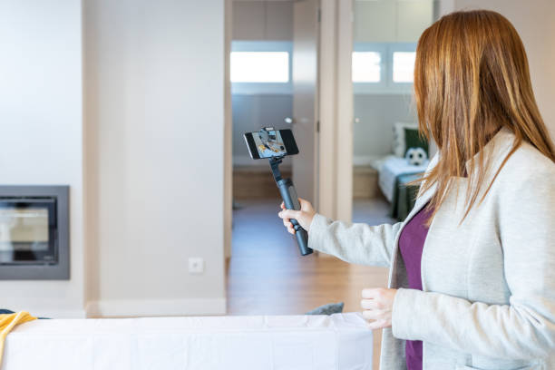 Female real estate agent making a video with her gimbal to show it to her clients in a video call or to upload it to social networks and promote the sale of a property or a property for sale. stock photo
