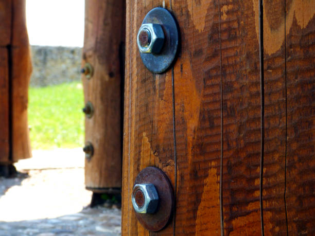 large steel bolts and galvanized nuts. wooden posts in closeup with fasteners. selective focus. blurred background. technology concept. wood structure. cracked stained wood texture